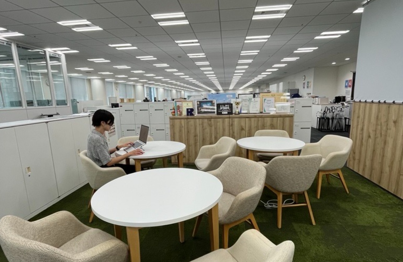 当社のオフィスはフリーアドレス制を採用しており、所属部署や役職に関係なく自由に席を選んで働くことができます。部署や役職の垣根を越えてコミュニケーションが生まれやすく、自然と社員同士の交流が活発になります。

写真のようなオープンスペースも設けており、集中して業務に取り組みたい時はもちろん、打ち合わせやちょっとした相談やミーティングが日常的に行われており、新卒社員も先輩社員と気軽に会話できる雰囲気があります。
社員同士の距離が近いため、困った時にすぐ質問できることも大きな魅力。新卒社員も先輩社員や上司とコミュニケーションを取りやすく、日々の業務を通じて成長できる環境が整っています。

「一人で抱え込まない」「周囲と協力しながら成果を出す」というカルチャーが、オフィス環境にも表れています。